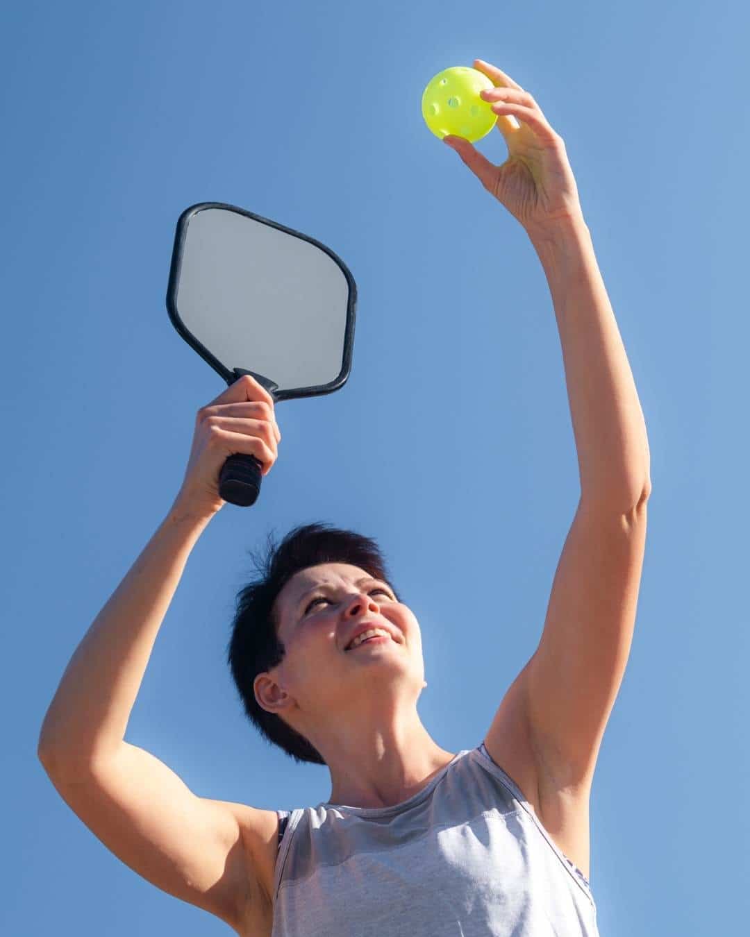 Raquette et balle de pickleball au soleil pour comparer le pickleball à d'autres sports