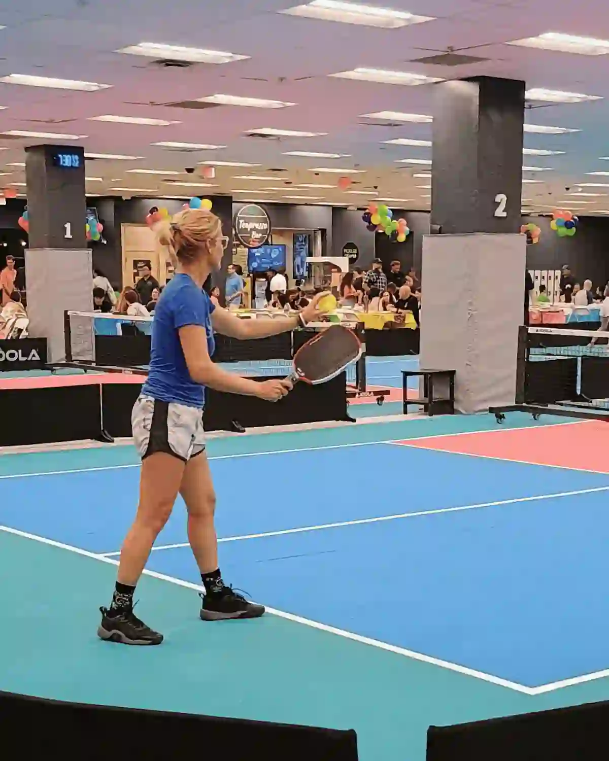 Service au pickleball en intérieur vu de côté