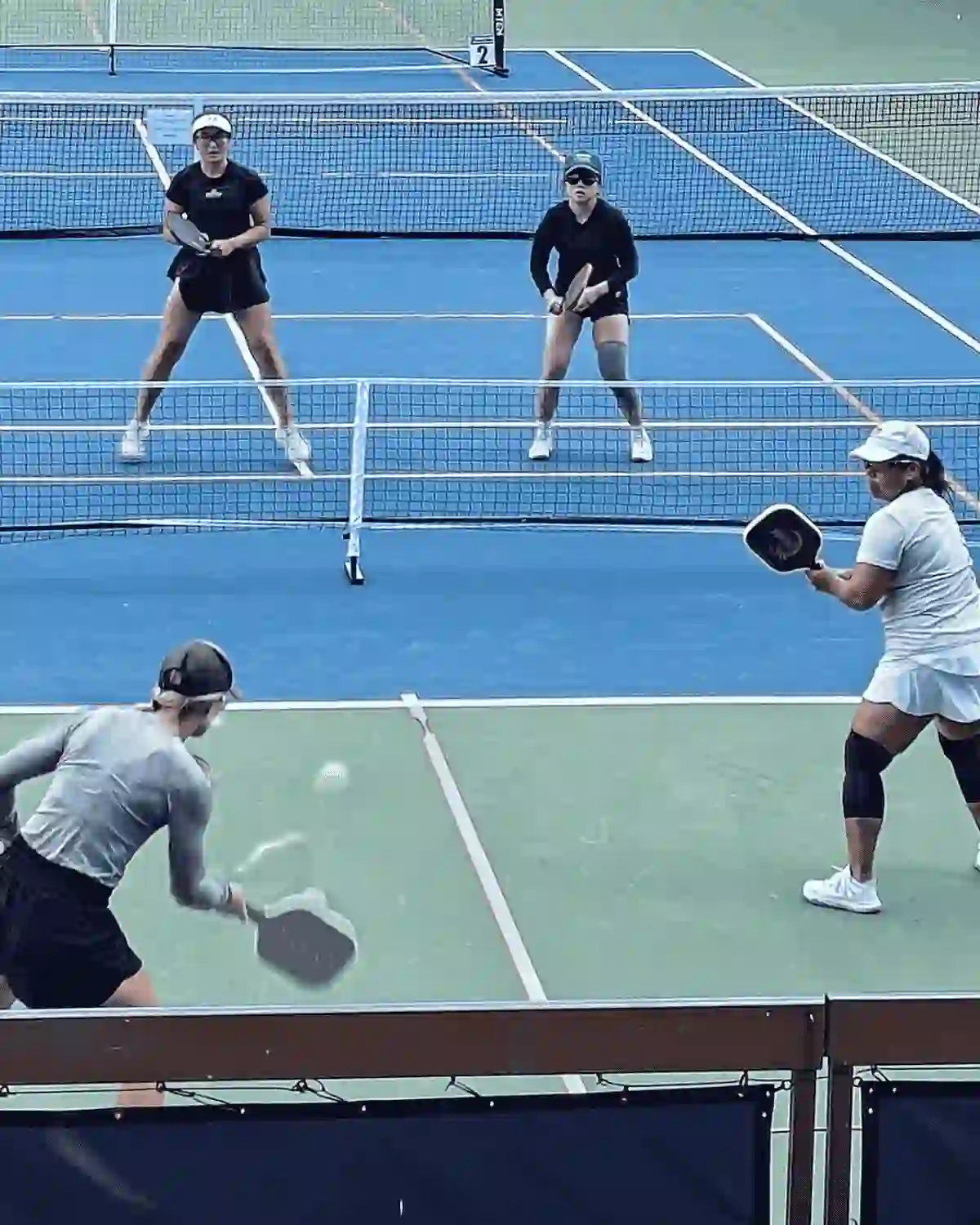 Quatre joueuses de pickleball pendant un match en extérieur