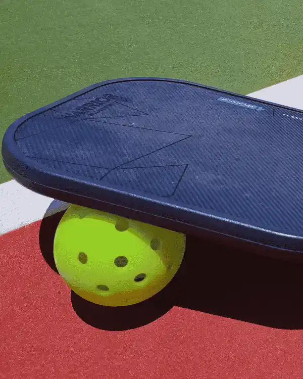 Raquette et balle de pickleball sur un terrain extérieur