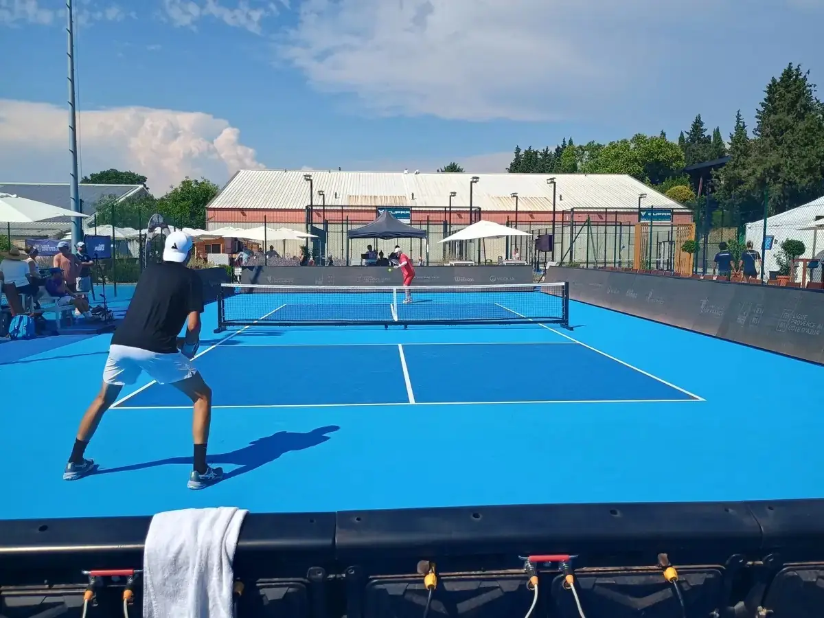 Joueur en fond de court face à un adversaire sur un terrain extérieur des Championnats de France de pickleball 2026