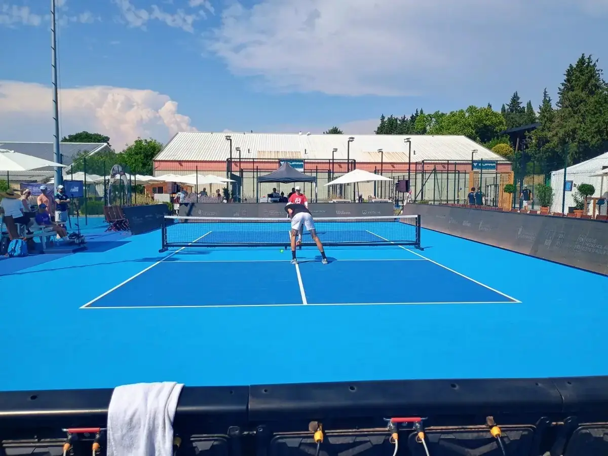 Joueur se penchant au filet sur un terrain extérieur des Championnats de France de pickleball 2026