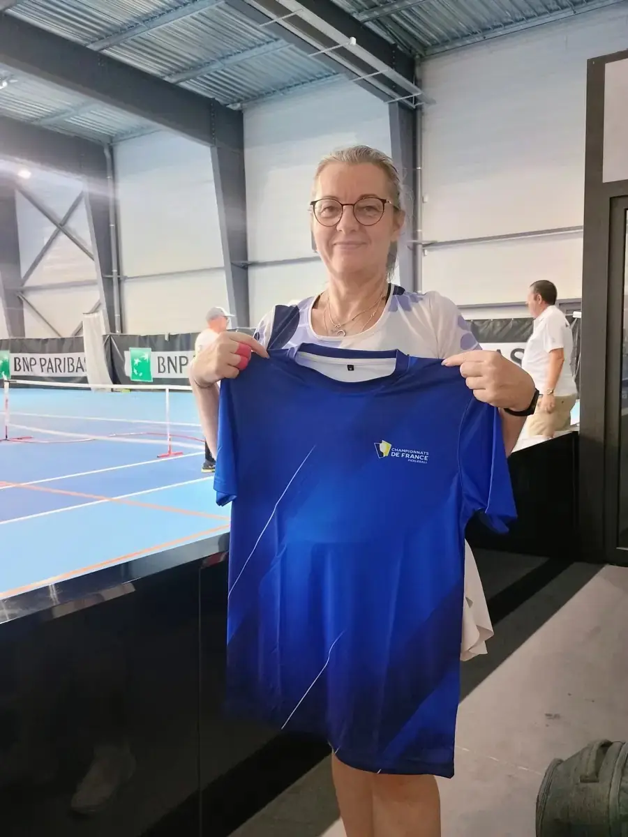 Karina Zaluski tenant le tee-shirt officiel des Championnats de France de pickleball 2026 dans le hall intérieur