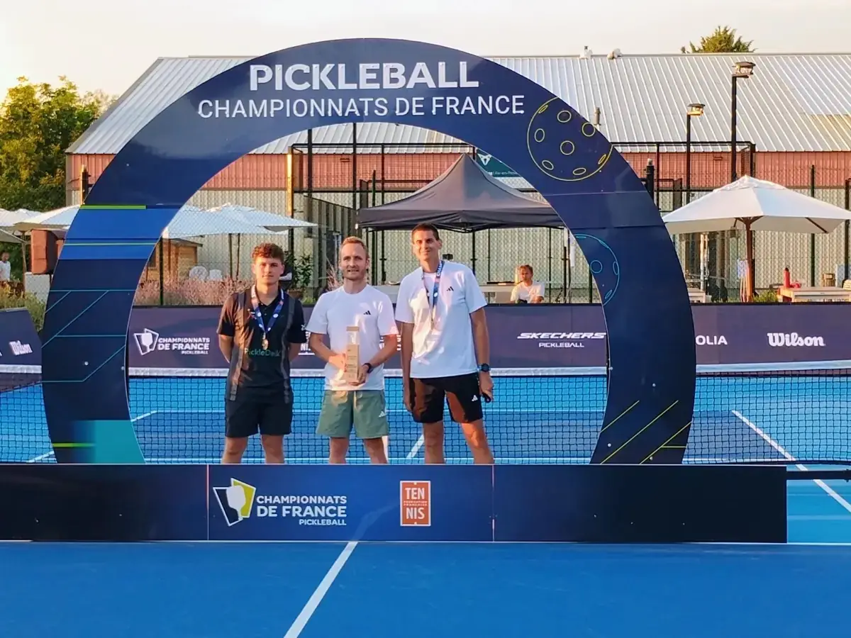 Podium de trois médaillés avec trophée sous l'arche des Championnats de France de pickleball 2026