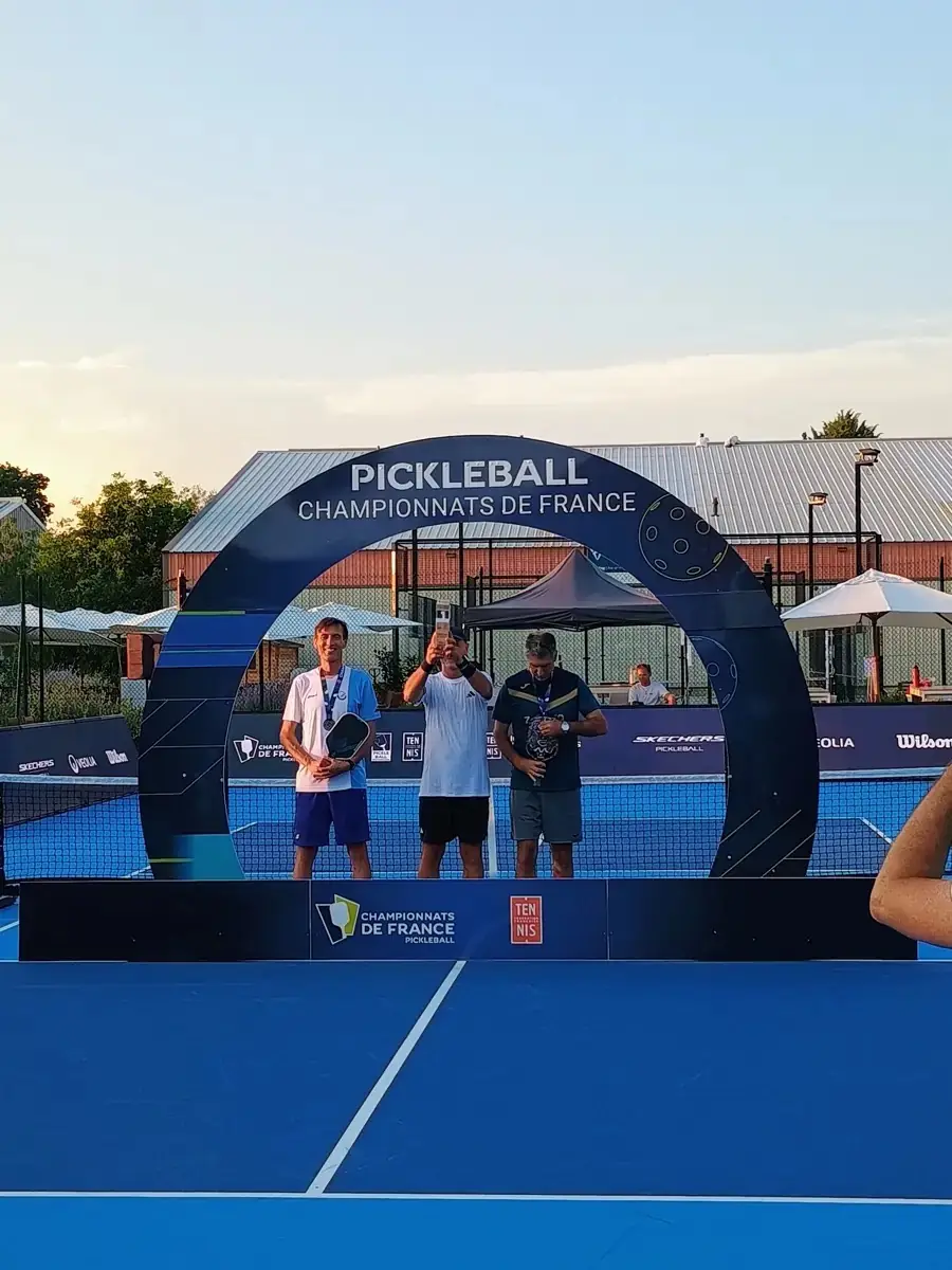Trois joueuses médaillées du simple posent sous l’arche officielle des Championnats de France de pickleball 2026