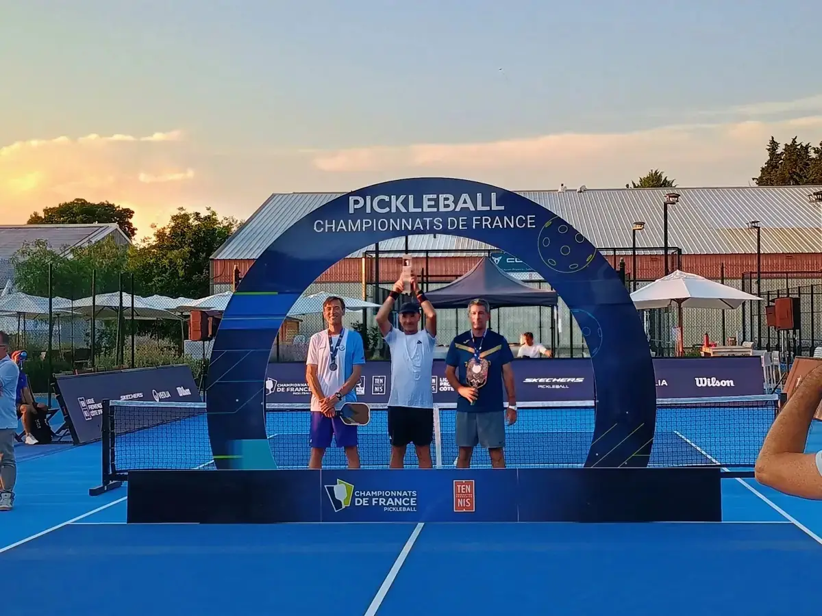 Autre podium masculin du simple avec le vainqueur levant son trophée sous l’arche officielle