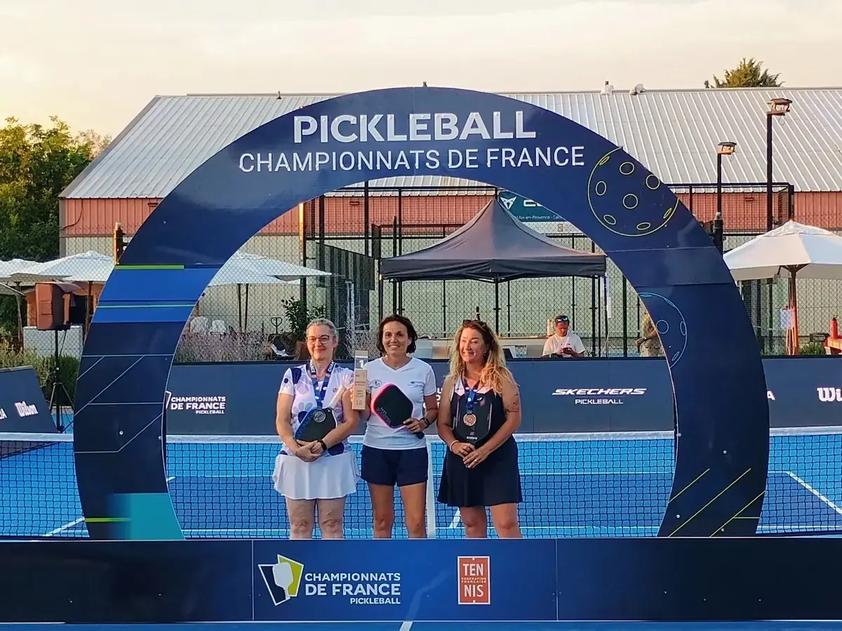 Trois joueuses médaillées du simple posent sous l’arche officielle des Championnats de France de pickleball 2026