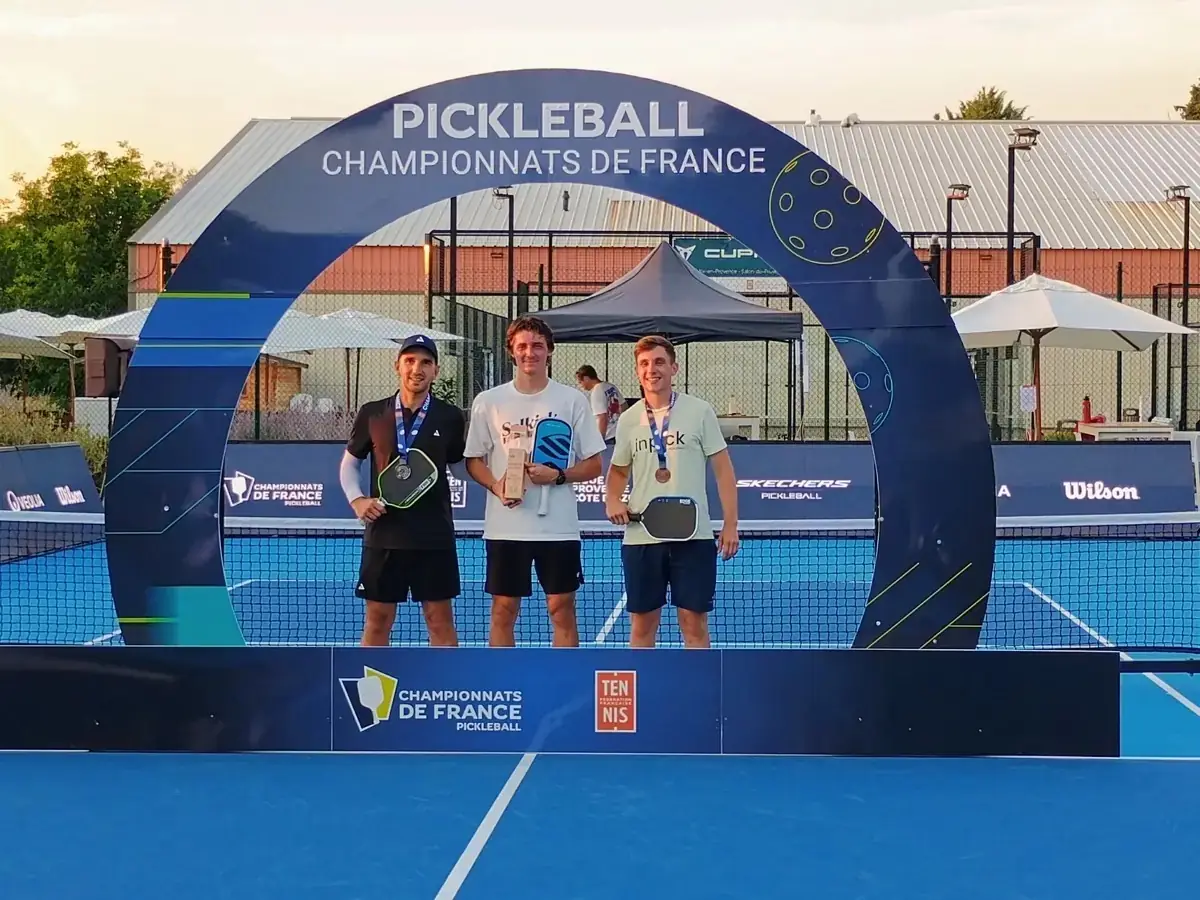 Trois médaillés masculins posent sous l'arche des Championnats de France de pickleball 2026