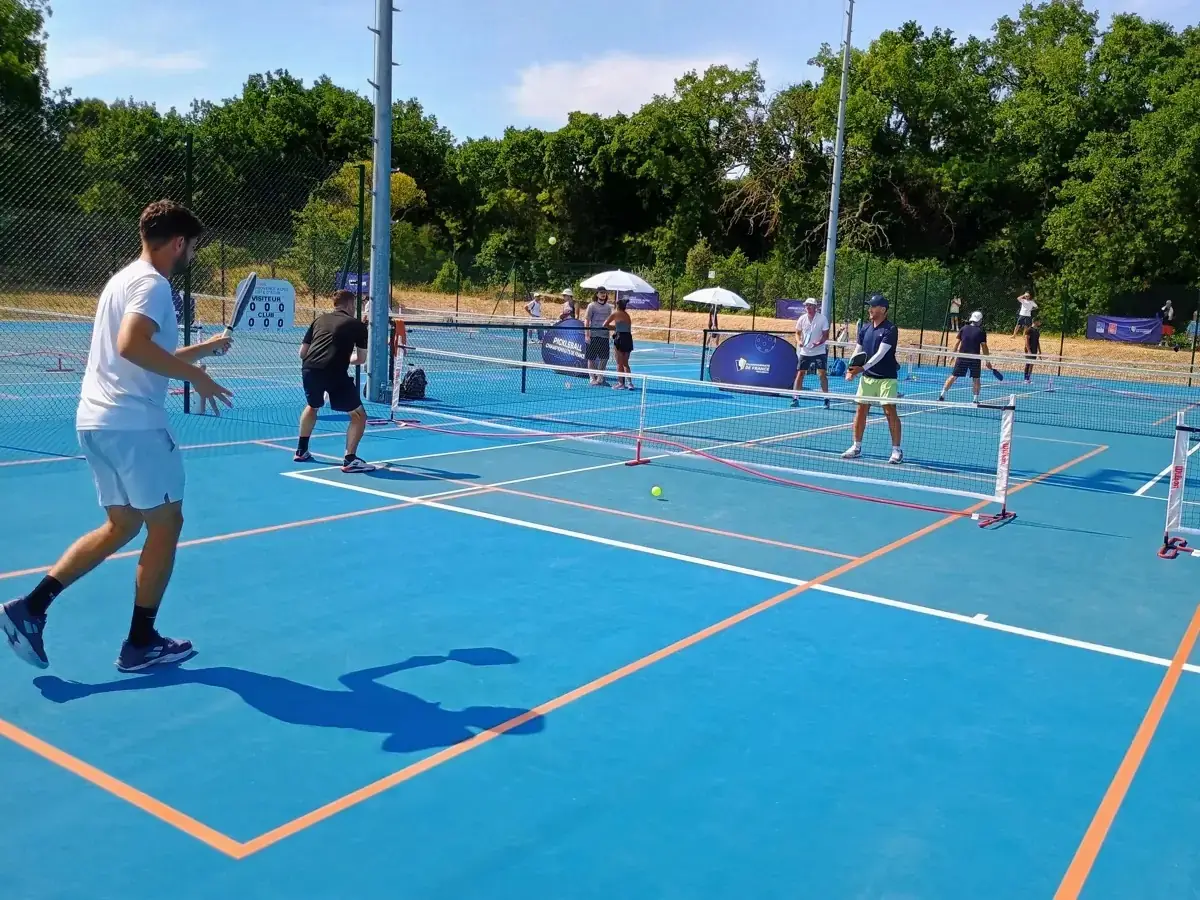 Joueur en blanc au filet pendant un match extérieur des Championnats de France de pickleball 2026