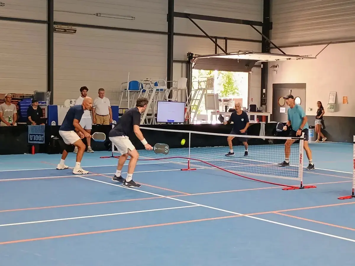 Échange en double sur un terrain intérieur des Championnats de France de pickleball 2026 avec joueurs au filet