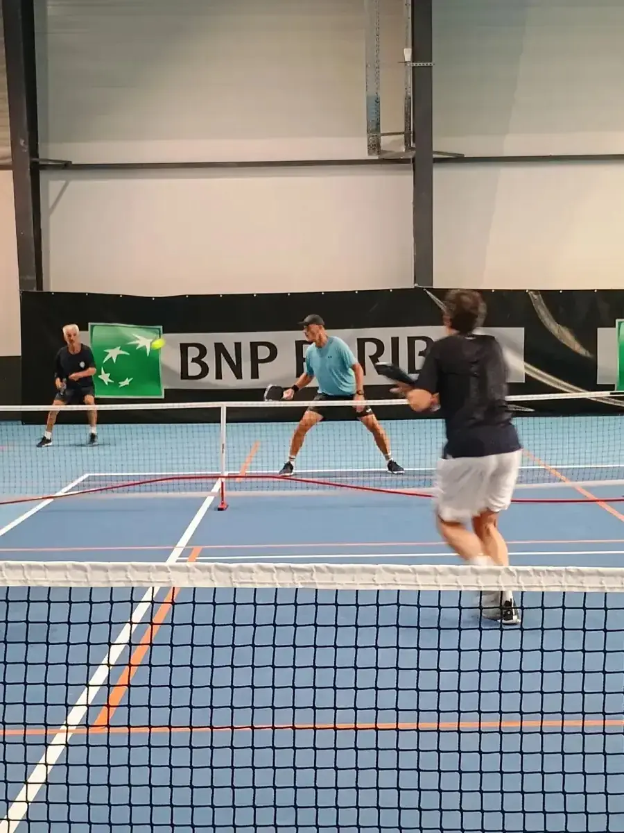 Joueur au filet sur un terrain intérieur des Championnats de France de pickleball 2026
