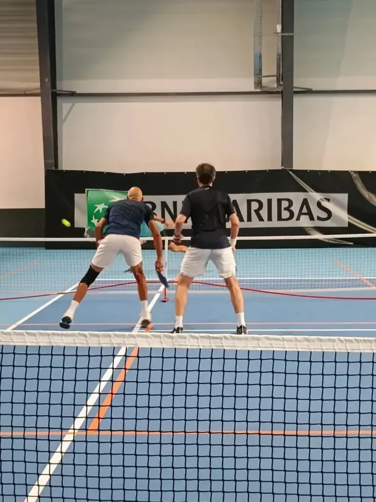 Deux joueurs près du filet sur un terrain intérieur des Championnats de France de pickleball 2026