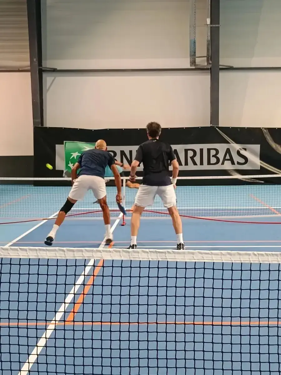 Deux joueurs près du filet sur un terrain intérieur des Championnats de France de pickleball 2026