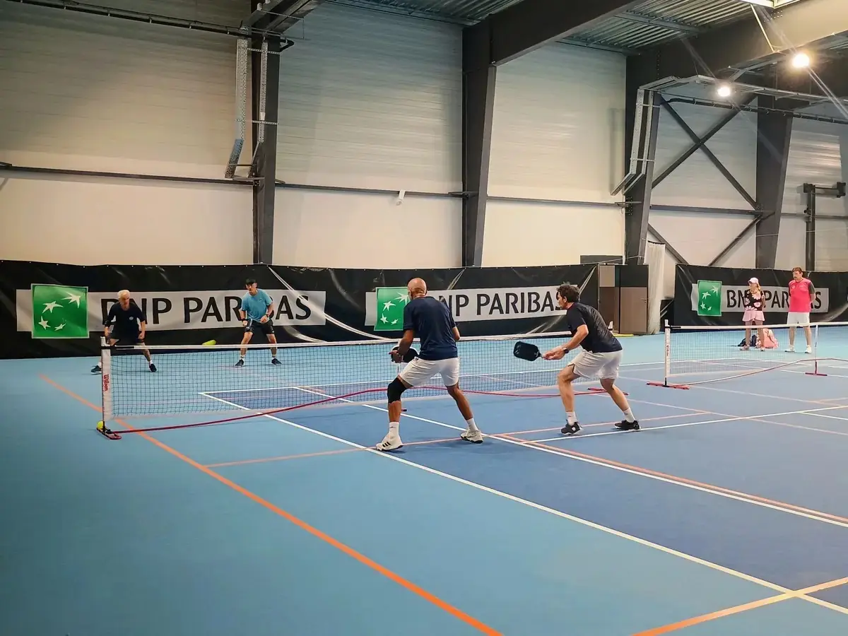 Échange en double sur un terrain intérieur vu à hauteur de filet aux Championnats de France de pickleball 2026