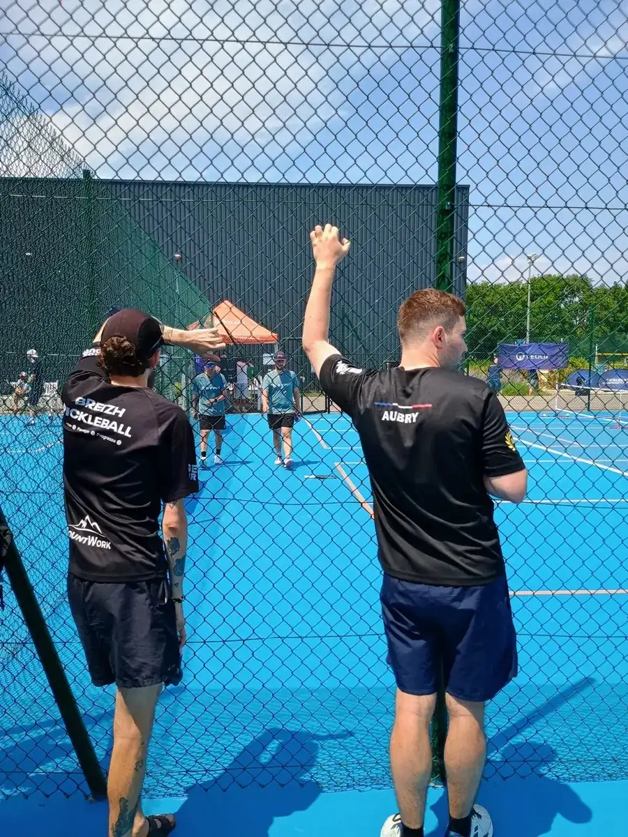 Deux hommes en noir célèbrent un point derrière le grillage des Championnats de France de pickleball 2026