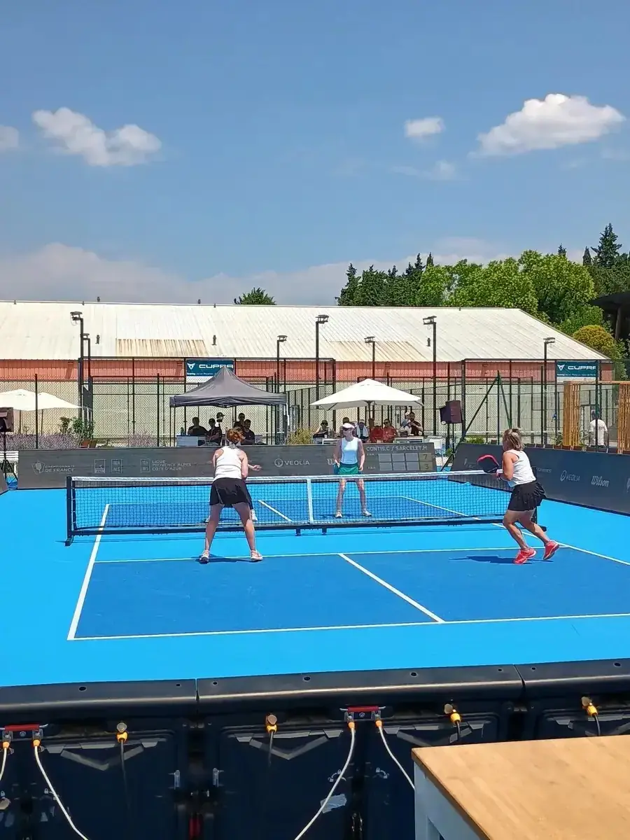 Match vu de côté sur le court extérieur principal des Championnats de France de pickleball 2026