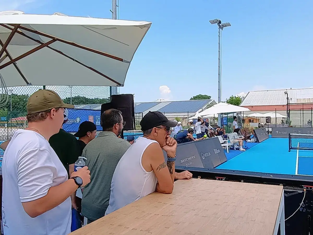Spectateurs accoudés au comptoir au bord d’un terrain extérieur des Championnats de France de pickleball 2026