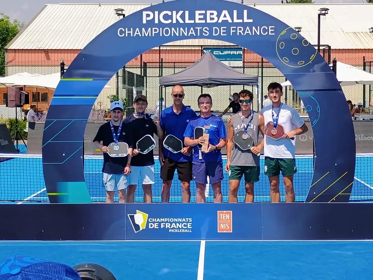Groupe de joueurs sous l’arche officielle des Championnats de France de pickleball 2026 à Aix-en-Provence
