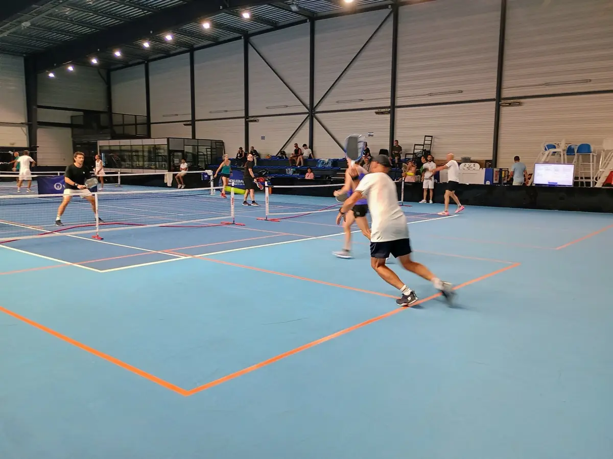 Vue large d'un échange sur plusieurs terrains intérieurs des Championnats de France de pickleball 2026