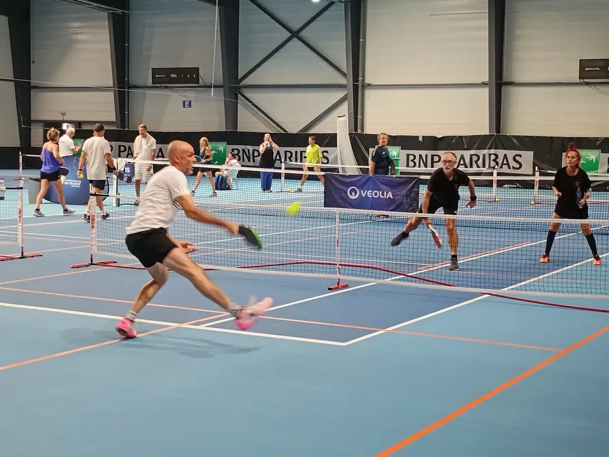 Joueur en extension latérale pendant un point sur les courts intérieurs des Championnats de France de pickleball 2026