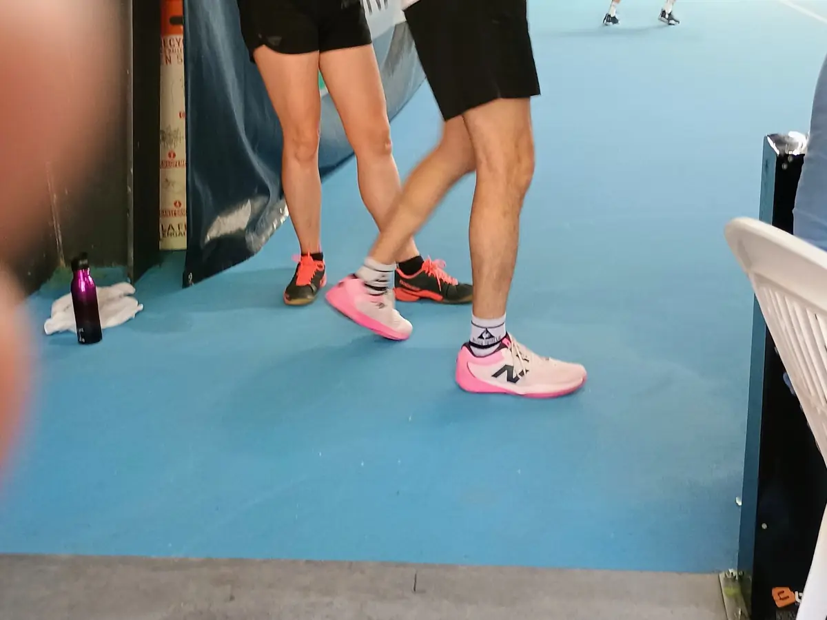 Détail de chaussures de pickleball au bord d'un terrain intérieur en compétition