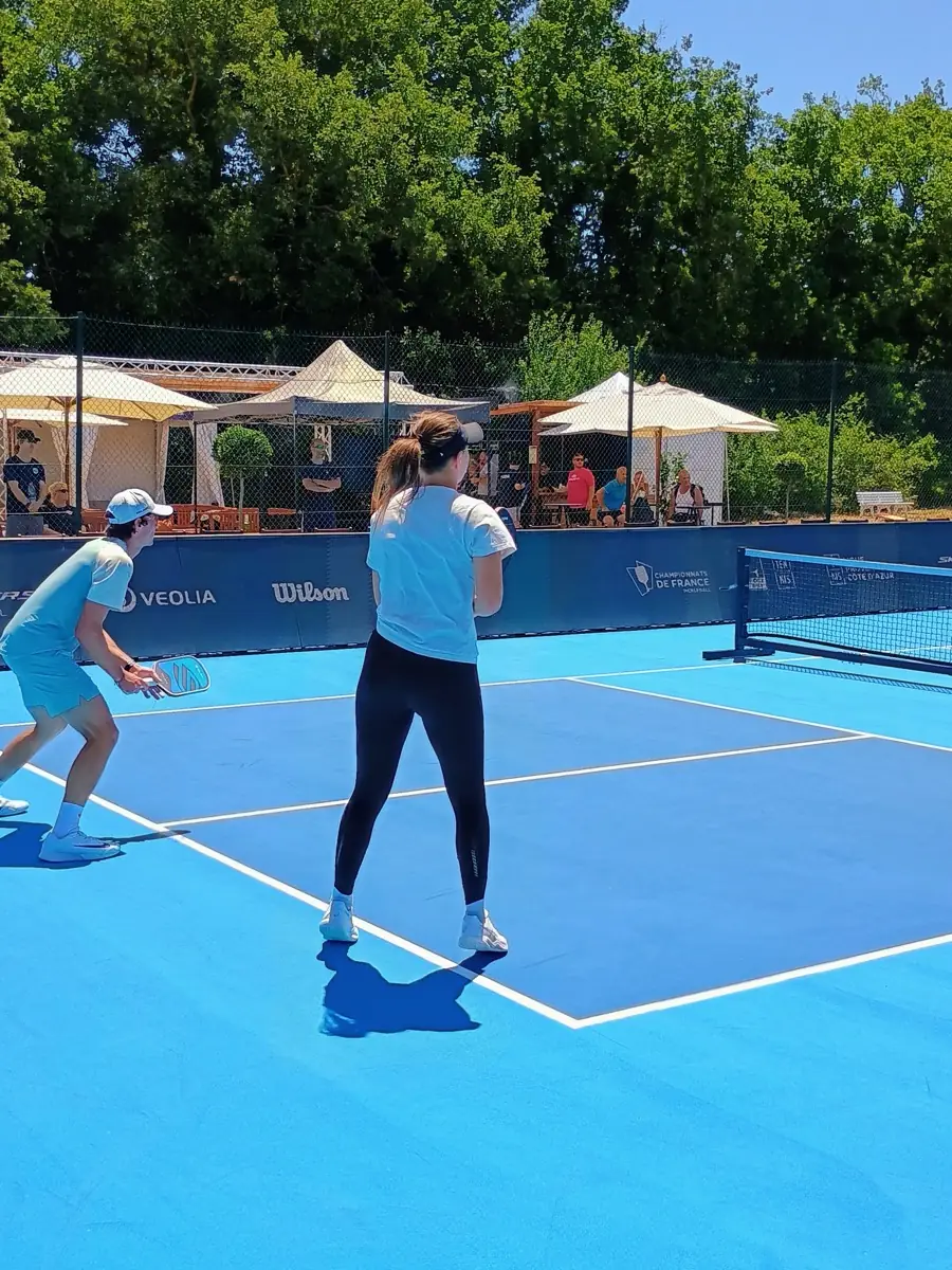 Joueuse en position d'attente sur un terrain extérieur des Championnats de France de pickleball 2026